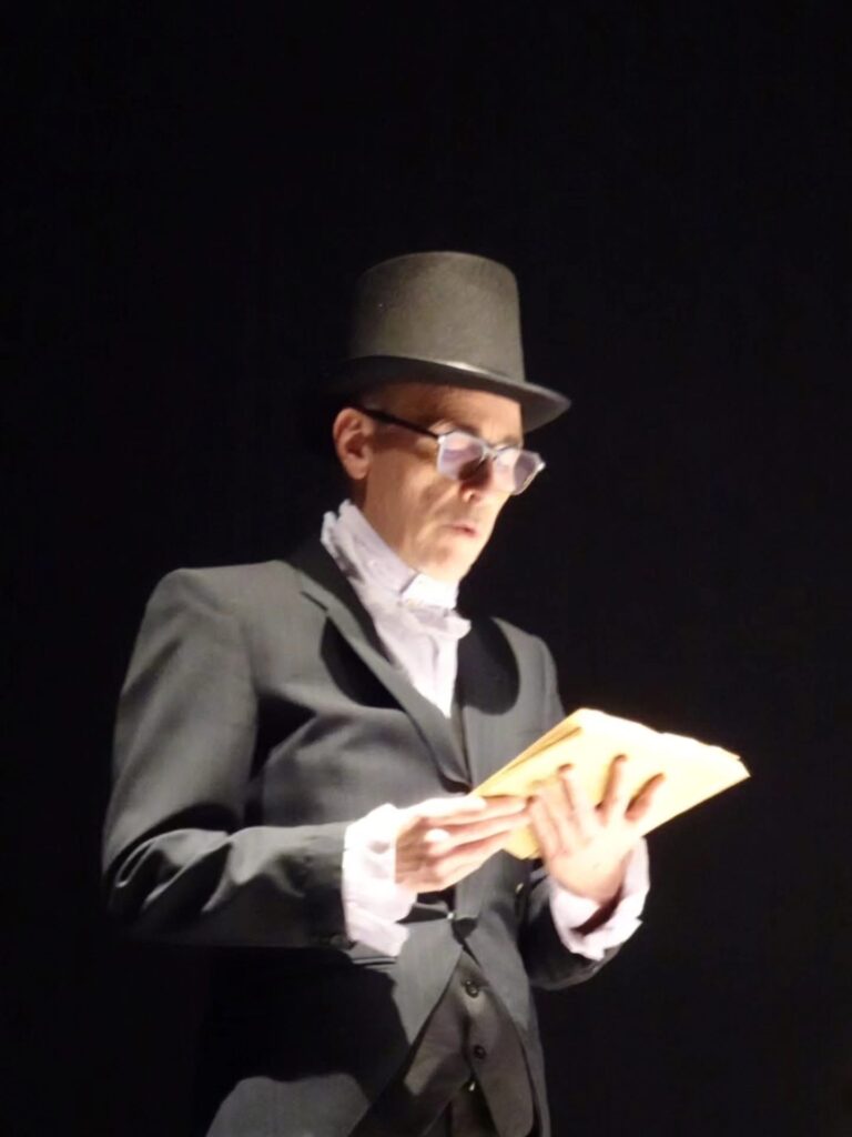 Un interprete con cilindro durante una lettura in scena